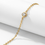 Close up of a gold bracelet with a clear gemstone on a white background