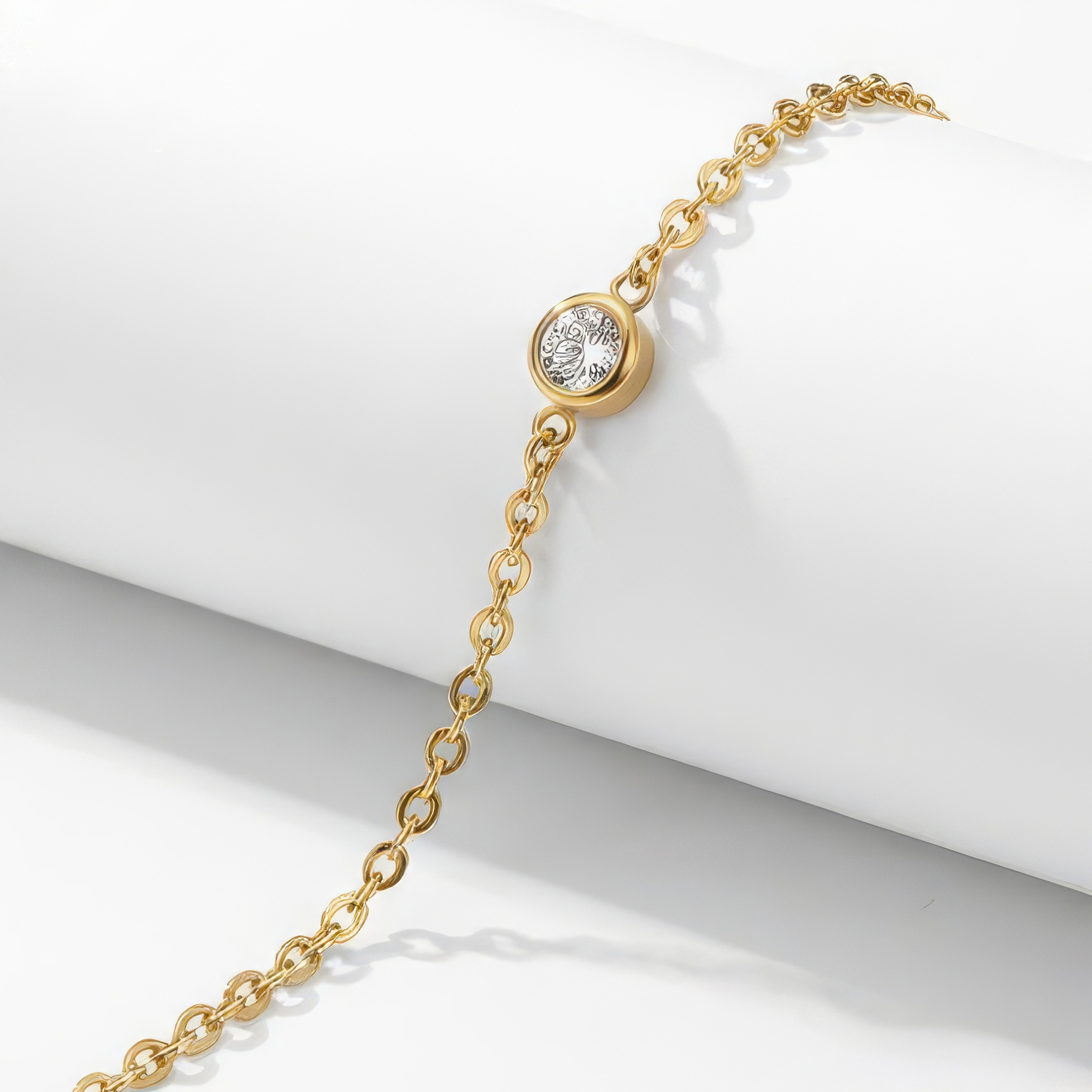 Close up of a gold bracelet with a clear gemstone on a white background