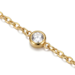 Close up of a gold bracelet with a clear gemstone on a white background
