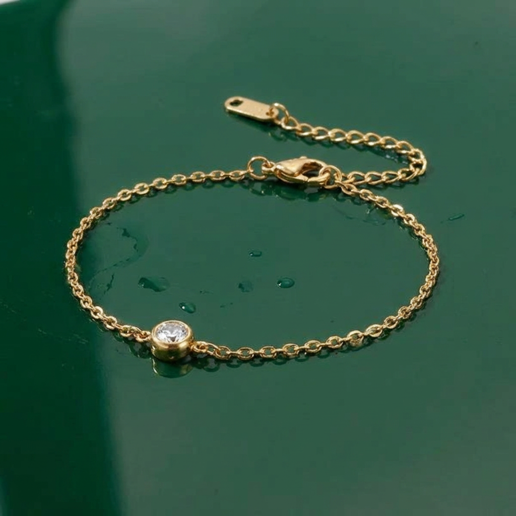 Gold bracelet with a central gemstone on a wet green surface