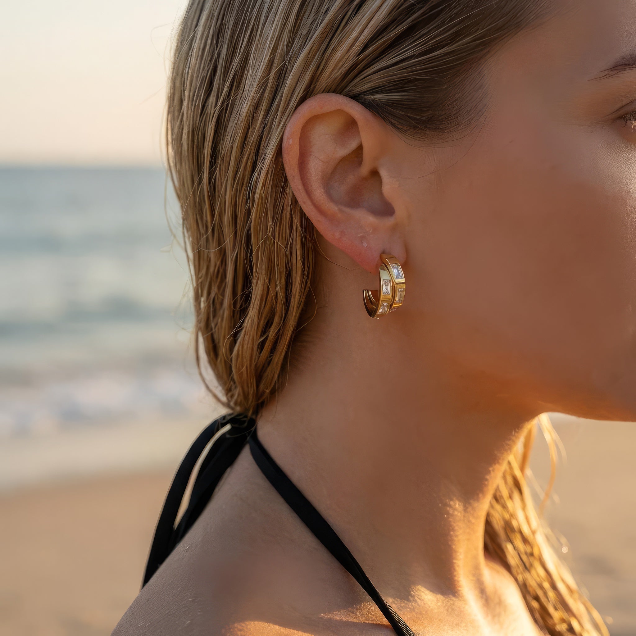 Gold hoop earrings on a woman at the beach