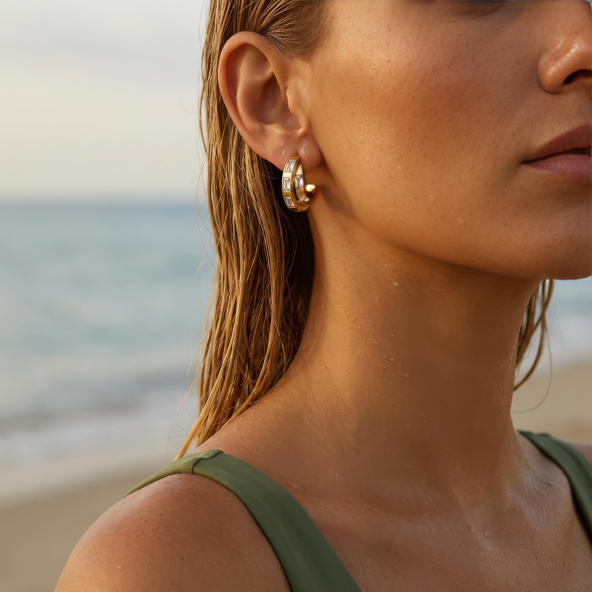 Close up of gold hoop earrings on a woman at the beach