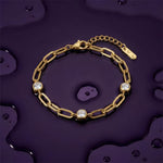 Gold chain bracelet with three diamond-like stones on a wet dark purple surface