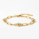 Gold chain bracelet with three diamond-like stones on a white background