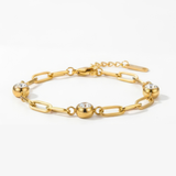 Gold chain bracelet with three diamond-like stones on a white background