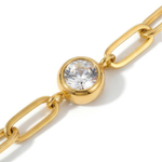 Close up of white gemstone on a gold chain bracelet on a white background