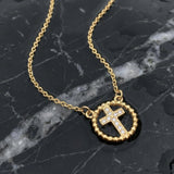 Gold cross necklace with rhinestones on a wet black marble surface