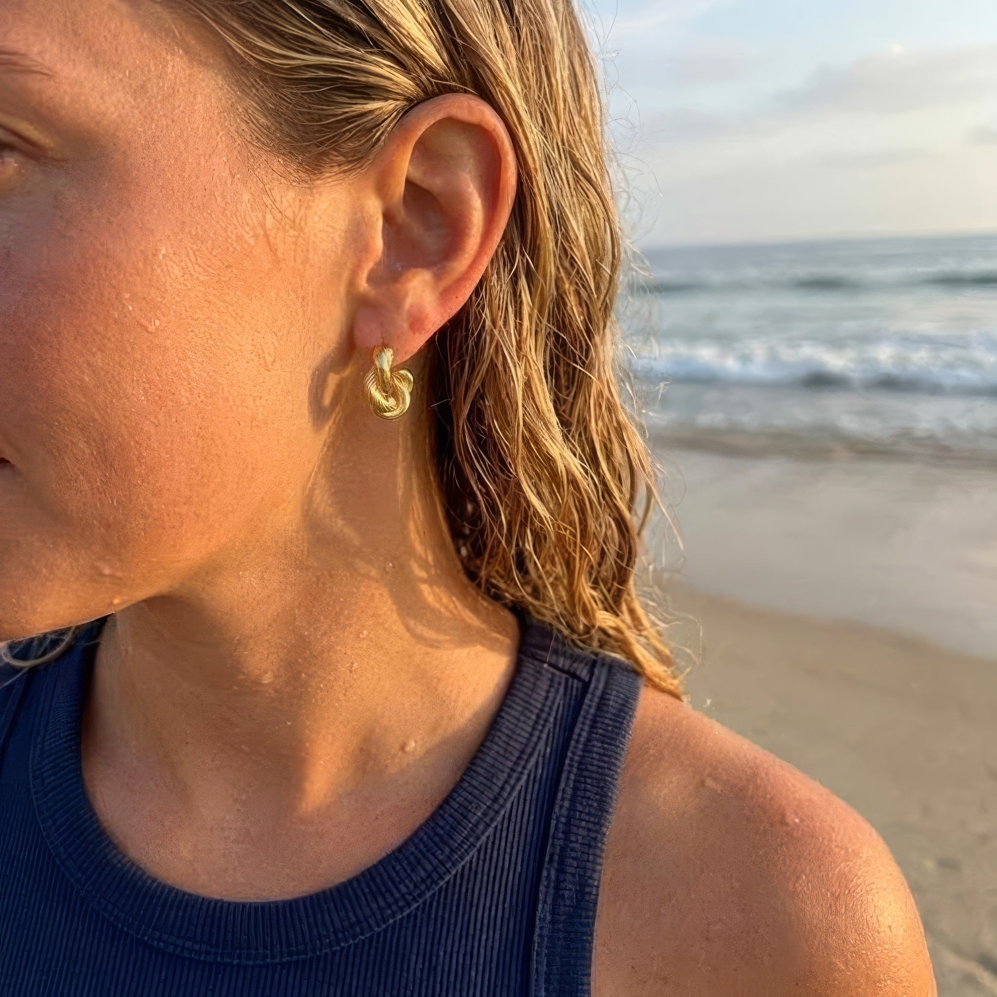 A woman wearing gold hoop earrings at the beach