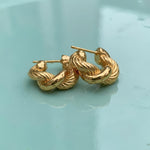 Gold hoop earrings on a wet turqouse surface