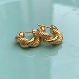 Gold hoop earrings on a wet turqouse surface
