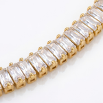 Gold bracelet with clear with baguette gemtones on a white background