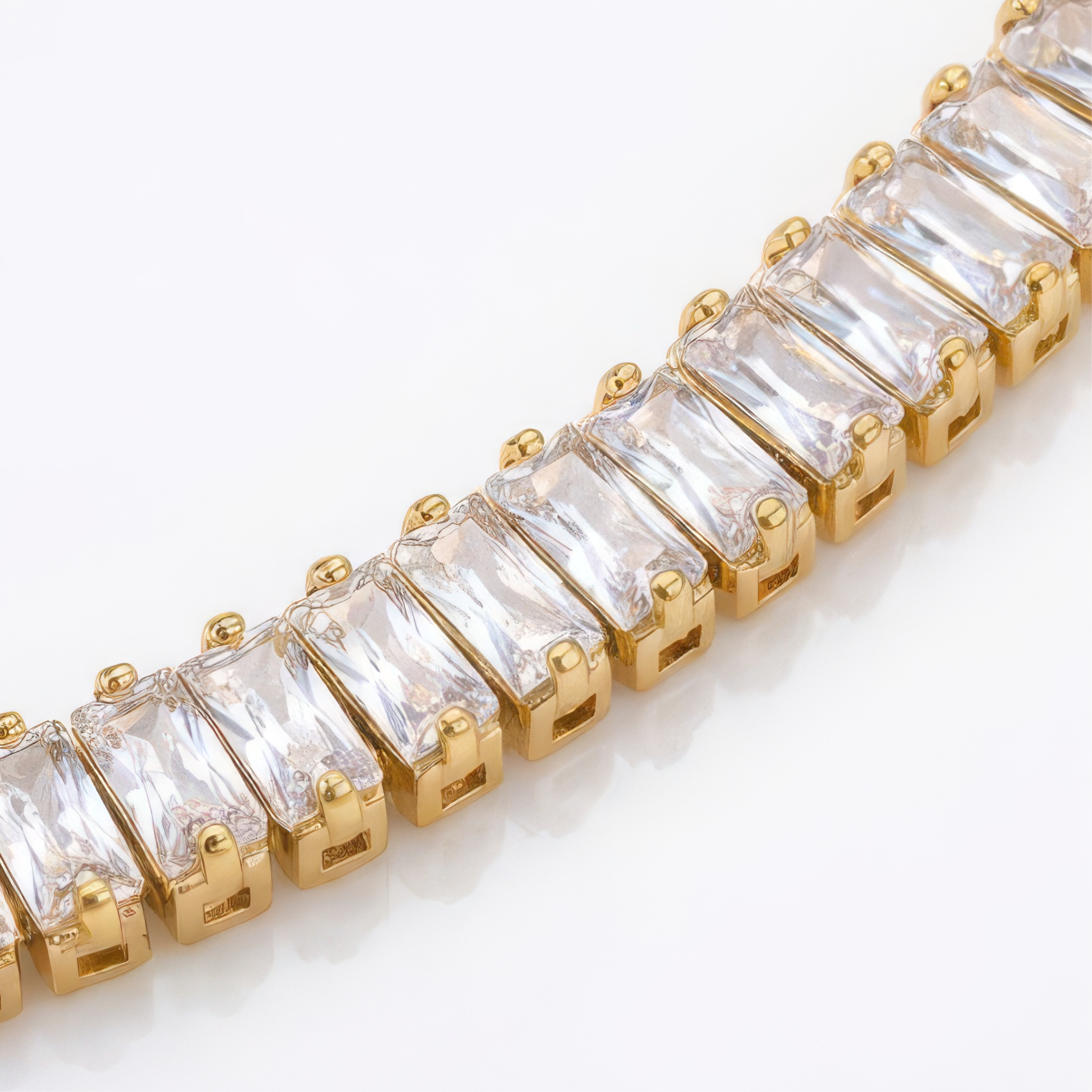 Gold bracelet with clear with baguette gemtones on a white background