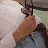 Mini Crosses Bracelet on a wrist of a woman who is leaning back