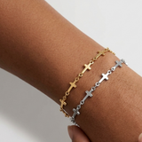 Two Mini Crosses Bracelet on a wrist with a white background. One is silver, one is gold.