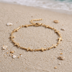 Mini Crosses Bracelet in the sand in front of the ocean.