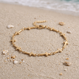 Mini Crosses Bracelet in the sand in front of the ocean.