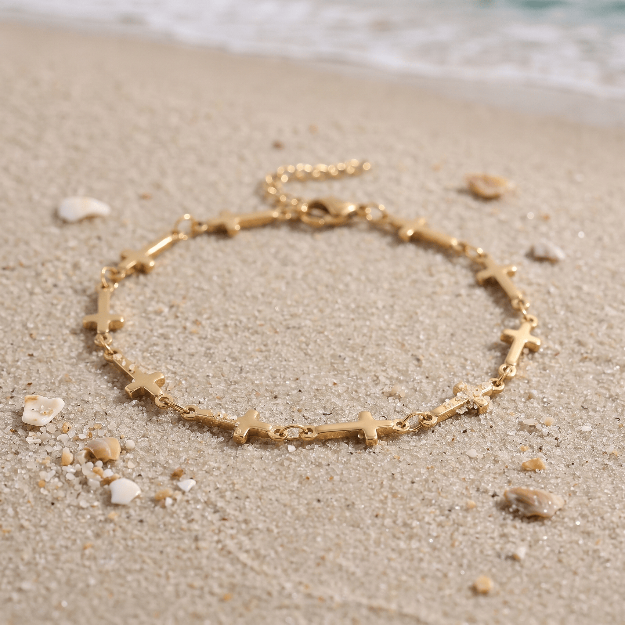 Mini Crosses Bracelet in the sand in front of the ocean.