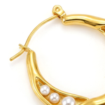Close up of a gold hoop earring with pearls on a white background