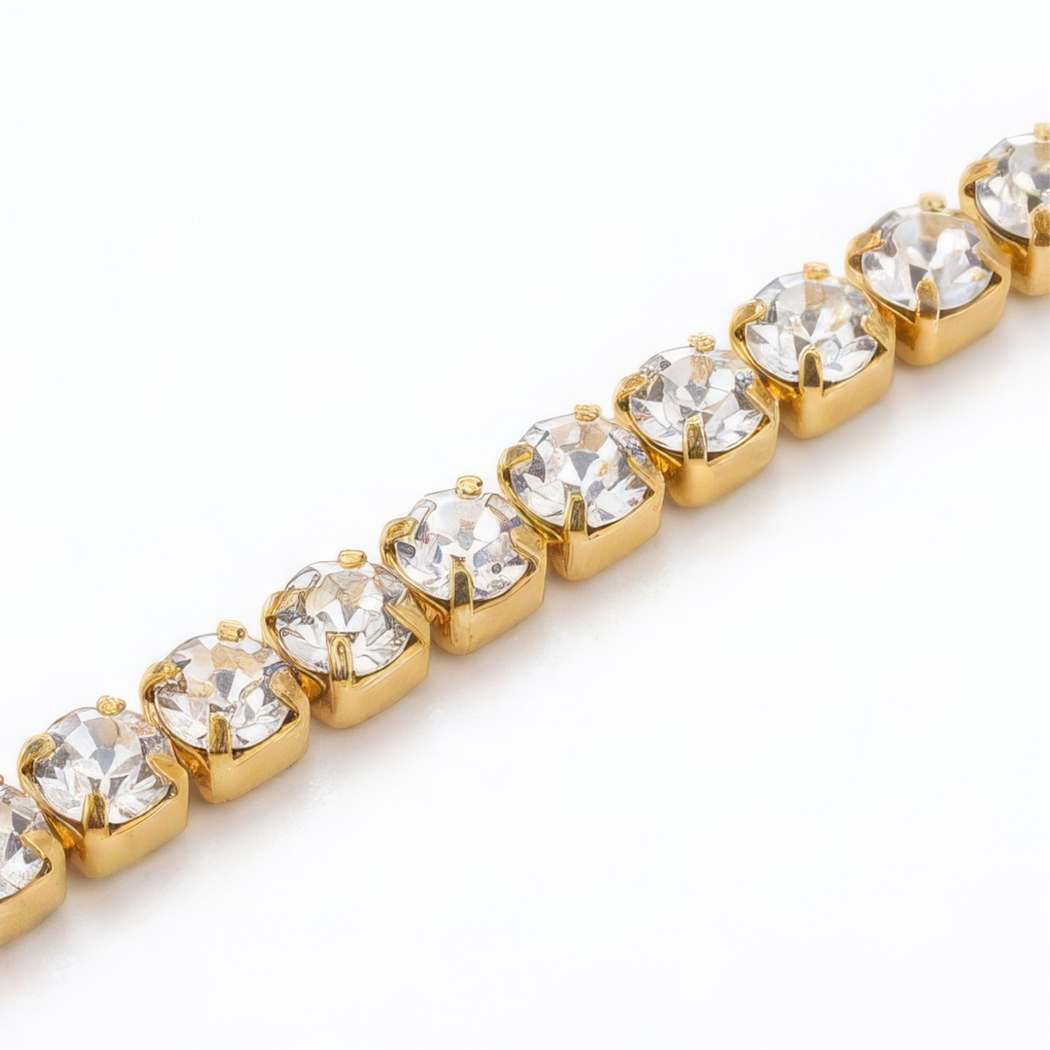 Gold bracelet with clear gemstones on a white background