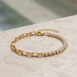 Gold bracelet with clear gemstones on a light stone surface at the edge of a pool
