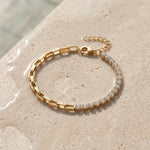 Gold bracelet with clear gemstones on a beige stone surface at the edge of a pool
