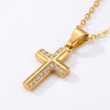 Gold cross pendant necklace with clear stones on a white background