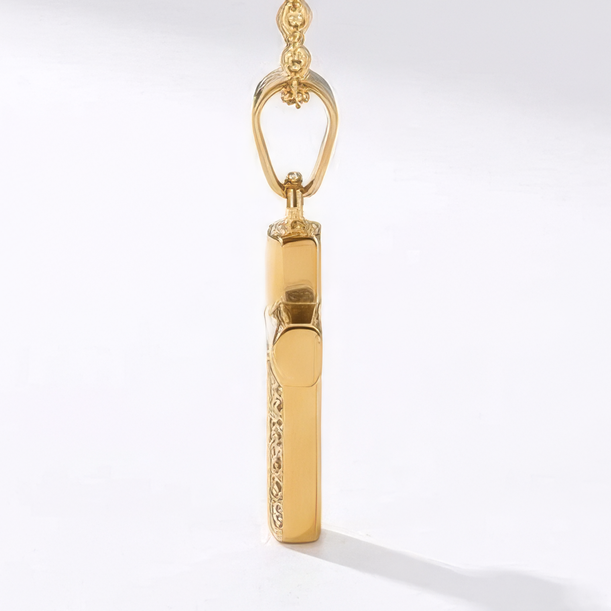 Side view of a gold necklace with a cross pendant on a white background
