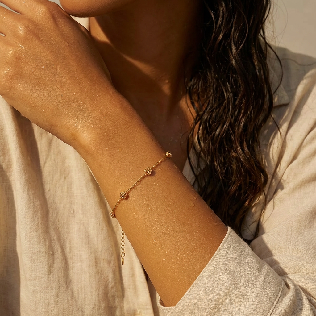 A woman wearing a gold bracelet with five stationary gold rosebud designs spaced out on the chain with a neutral background