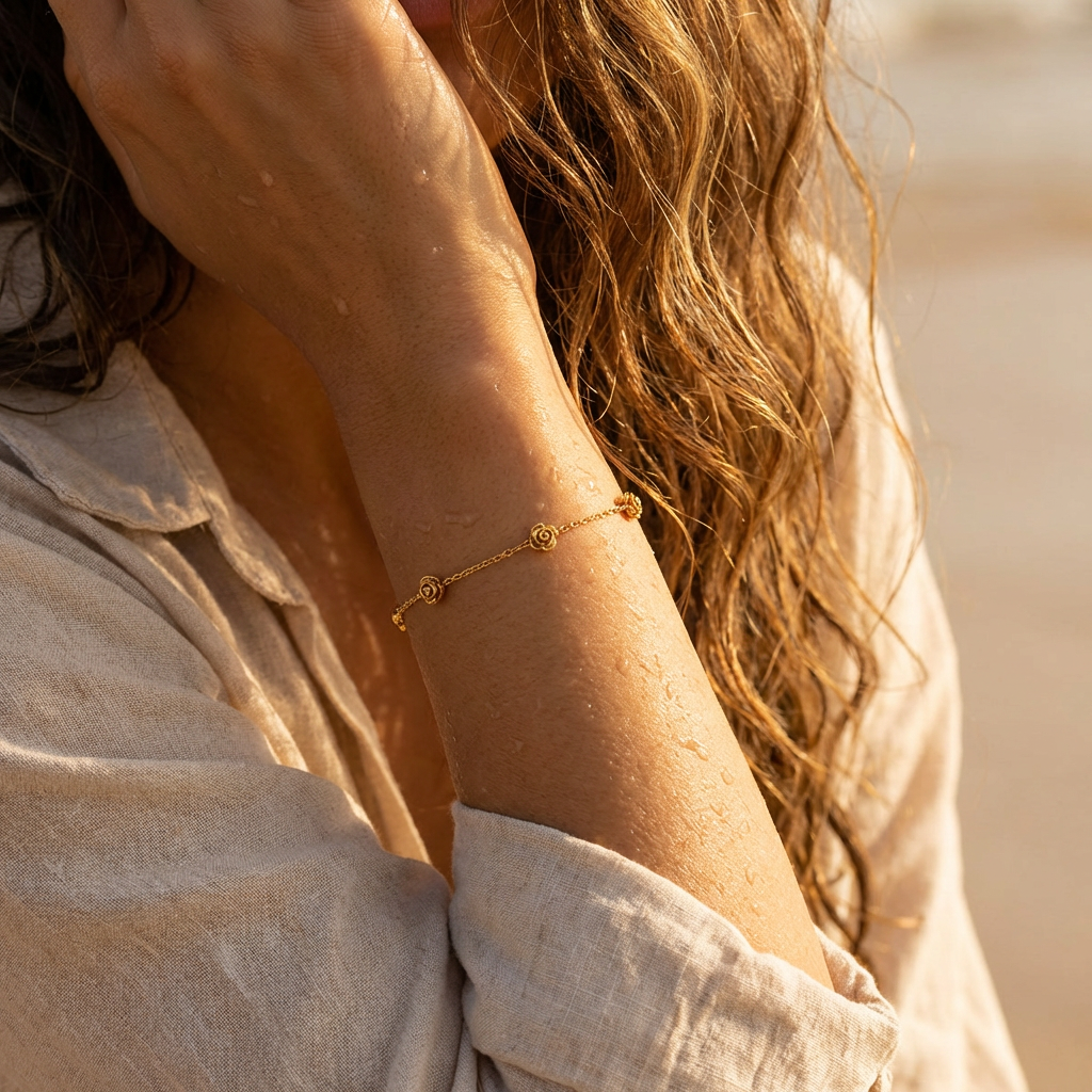 A woman wearing a gold bracelet with five stationary gold rosebud designs spaced out on the chain with a neutral background