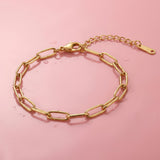 Gold paperclip chain bracelet on a wet pink surface