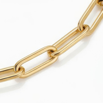 Close up of links of gold paperclip chain bracelet white background