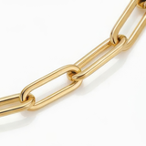 Close up of links of gold paperclip chain bracelet white background