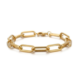 Close up of gold paperclip chain bracelet on a white background
