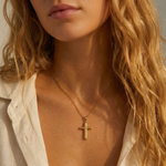 Woman wearing a gold cross necklace.