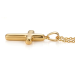 Gold cross necklace lying sideways on a white background.